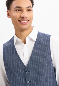 Marineblau gestreifter Weste aus strukturiertem Stoff, mit V-Ausschnitt, drei Knöpfen und getragen über einem weißen Hemd mit Kragen.