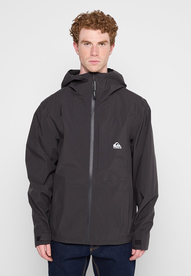 Chaqueta negra impermeable con capucha, cremallera frontal y detalle de logo en el pecho. Presenta mangas largas y puños ajustables.