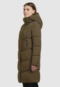 Olivenfarbene gepolsterte Jacke mit Kapuze, vertikalen Nähten, Reißverschlusstaschen und einer leicht taillierten Silhouette. Glatte Stofftextur.