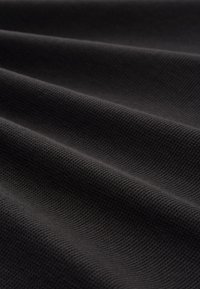 Sort tekstureret stof med et gittermønster, der viser glatte, foldede overflader, som skaber bløde bølger og skygger.