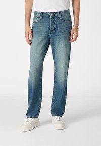 Lichtblauwe denim jeans met een comfortabele pasvorm, voorzien van vijf zakken, een knoopsluiting en subtiele vervaging in de buurt van de dijen en knieën.
