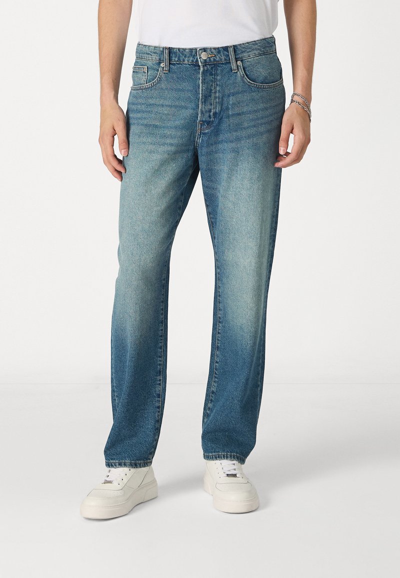 Lichtblauwe denim jeans met een comfortabele pasvorm, voorzien van vijf zakken, een knoopsluiting en subtiele vervaging in de buurt van de dijen en knieën.