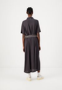 Robe gris foncé, arrivant au genou, avec des manches courtes, un col et une taille cintrée. Elle comporte une ceinture décorative et une texture douce.