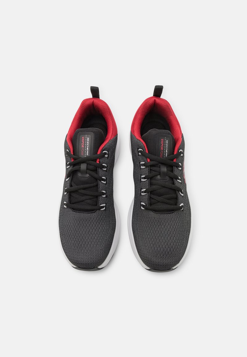 Zapatillas deportivas negras con una parte superior de malla texturizada, detalles rojos en el cuello, cordones negros y suelas blancas con un diseño liso.