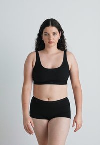 Svart underklädesset som består av en scoop-neck bralette och högmidjade shorts. Tillverkat av mjukt, elastiskt tyg med en slät yta.