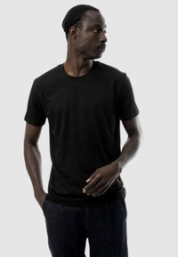 T-shirt nera in cotone con maniche corte, scollo rotondo e vestibilità rilassata. Il tessuto sembra liscio e leggero.