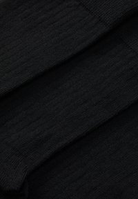 Fekete kötött anyag bordázott textúrával, több réteggel és sima felülettel. Ruházat vagy kiegészítők tervezésére alkalmas.