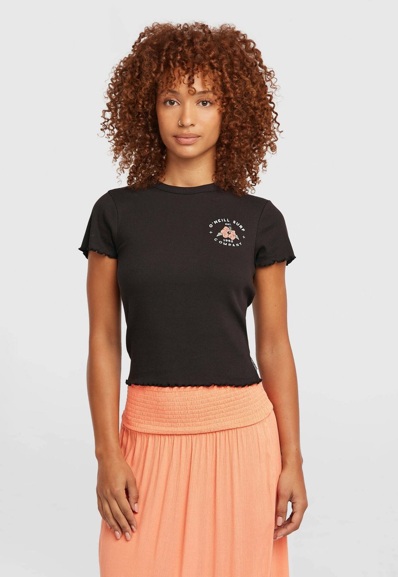 Camiseta negra de manga corta con costillas y bordes festoneados, con un logo floral. Combinada con una falda fluida naranja con cintura fruncida.