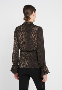 Blusa nera con stampa leopardata caratterizzata da una vita arricciata, maniche a campana e un tessuto morbido e trasparente. La vista dal retro mostra un colletto e una finitura liscia.
