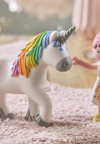 Unicorn toy in white plastic with a rainbow mane and gray hooves. A pink-haired figurine in a floral dress interacts with the unicorn.