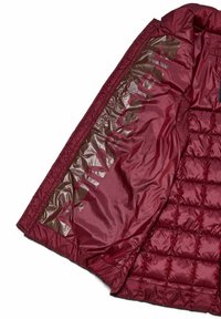 Giacca a vento maroon con texture trapuntata e rivestimento interno marrone lucido, caratterizzata da grande scritta in rilievo lungo il pannello interno.
