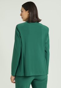 Grüner Blazer mit lässiger Passform, strukturierten Schultern und langen Ärmeln. Glatter Bezug, Rücken-Schlitz und schlichtes Design.