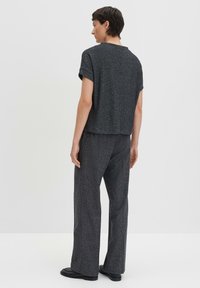 Haut gris à manches courtes avec une coupe décontractée, fabriqué en tissu texturé. Associé à un pantalon large assorti. Design simple et minimaliste.