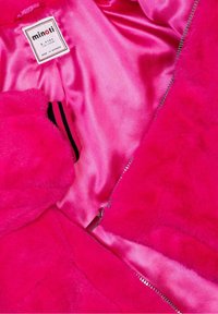 Giacca in pelliccia finta fucsia con un interno in raso rosa lucido; dotata di zip e dettagli con etichetta. Morbida al tatto, colore vivace.