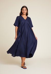 Mørkeblå linkjole med V-hals, korte oppbrettede ermer og en luftig A-line silhuett, med en lett tekstur og midt på leggen lengde.