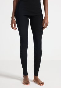 Svarta leggings gjorda av elastiskt tyg, med en åtsittande design och hel-längd, som har en slät yta och inga synliga mönster.