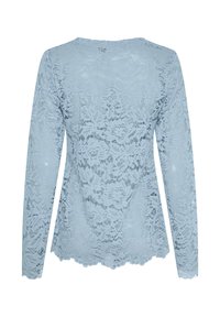 Lyseblå blonder med lange ærmer, prydet med blomsterprint, bølget kant og en afslappet pasform. Delikat, semi-gennemsigtigt materiale.