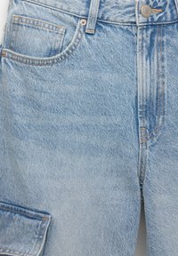 Svetlo modré džíny z denimu s tradičným dizajnom piatich vreciek, viditeľným prešívaním a jemnou textúrou so slabým vyblednutím.