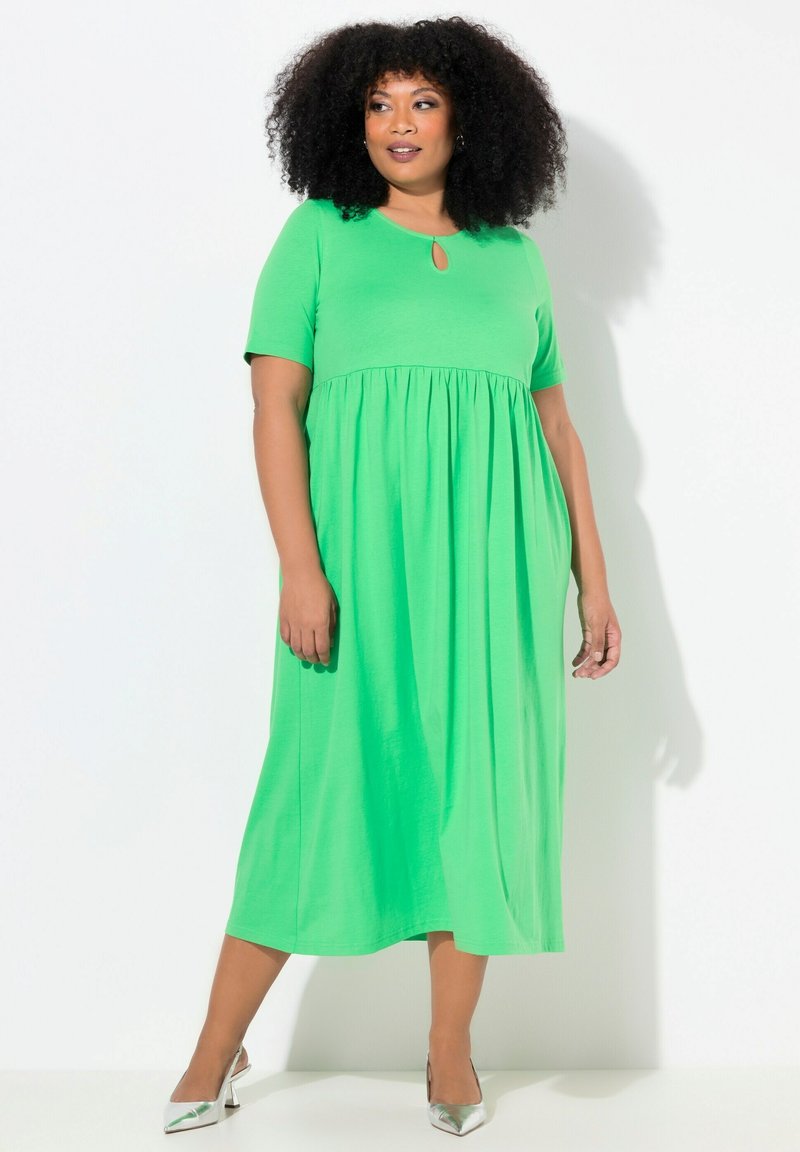 Vihreä midi-mekko lyhyillä hihoilla, volyymilla varustettu hame ja avainaukko-yksityiskohta kaula-aukossa. Tasainen kangas, rento malli, ja yhdistetty hopeakorkokenkiin.