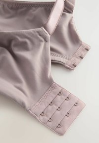 Soutien-gorge en lavande claire avec tissu lisse, une bretelle réglable et six crochets avec boucles pour la fermeture. Présente des bords doux et un design sans coutures.