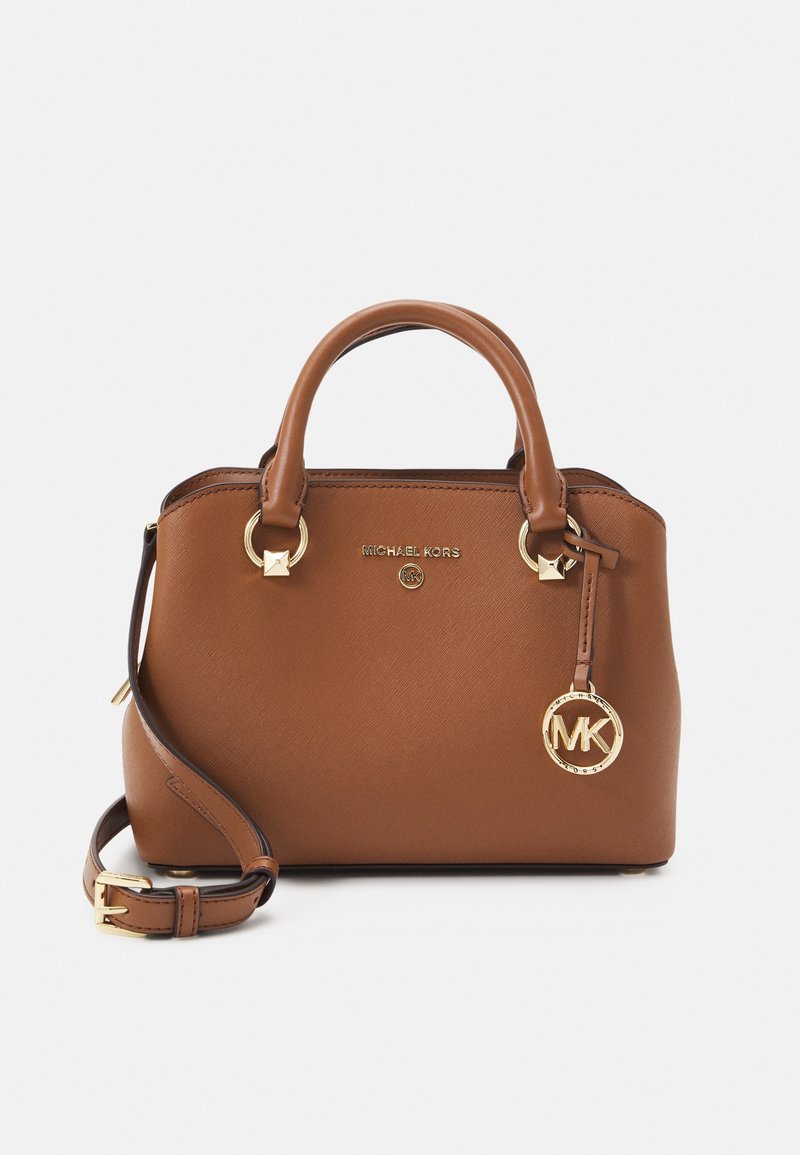 Sac à main en cuir marron Michael Kors avec doubles poignées, bandoulière réglable et bijou doré avec logo MK suspendu à une poignée.