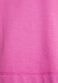 Tela de color fucsia que muestra una superficie suave, ligeramente texturizada con un sutil patrón jaspeado y un dobladillo limpio y cosido en la parte inferior.