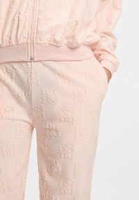 Roze trainingspak met reliëf "Hugo" logo patroon, voorzien van een elastische tailleband en manchetten, zachte stoftextuur en een aansluitend ontwerp.