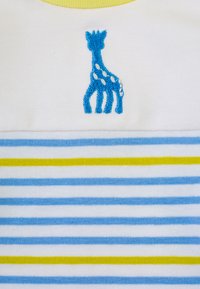 Camicetta a maniche corte con colletto giallo, caratterizzata da una giraffa ricamata blu e righe orizzontali in blu e giallo su uno sfondo bianco.