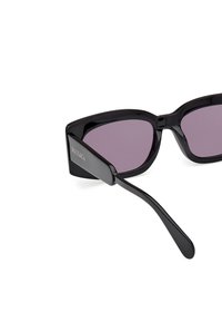 Gafas de sol de ojo de gato negro con lentes oscurecidos, acabado brillante y un diseño elegante y angular. Presenta la marca en la patilla.