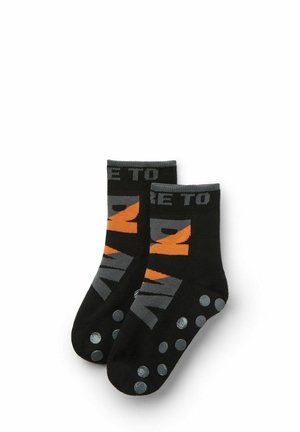 Calze nere con testo grigio e arancione, con bordo corto e puntini di presa in gomma sui fondi per una maggiore aderenza.
