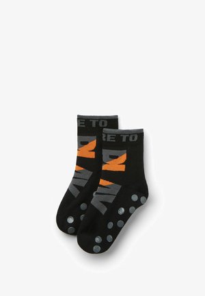 Schwarze Socken mit grauem und orangefarbenem Text, einem kurzen Bündchen und mit gummierten Grip-Punkten auf der Sohle für zusätzlichen Halt.