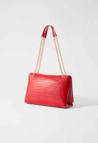 Borsa in ecopelle rossa a forma di crocodylo, caratterizzata da una forma strutturata, cinturini in catena dorata e una superficie liscia con una finitura lucida.