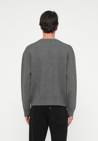 Grå hettegenser med rund hals, ribbestrikket kant og mansjetter, samt en avslappet passform. Myk tekstur, ensfarget design og sømløs bak.