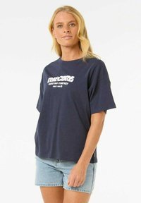 Camiseta de algodón azul marino con un corte relajado y mangas cortas; presenta el logo en texto blanco "Surfing Company" en el pecho.