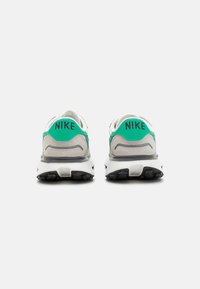 Zapatillas Nike con parte superior blanca y gris, acento verde en el talón, suela de goma negra y marca visible en la parte posterior.