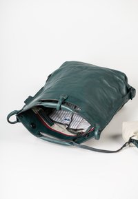 Turquoise leren tas met een gestructureerde buitenkant. Binnenin bevindt zich een gestreepte voering, een rode accentkleur en een grijze pouch. Inclusief verstelbare schouderriem.