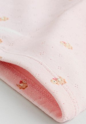 Heller rosa Stoff mit gestickten Hühner-Motiven, versehen mit einer strukturierten Webart und kleinem Punktmuster. Sichtbarer gefalteter Saum.