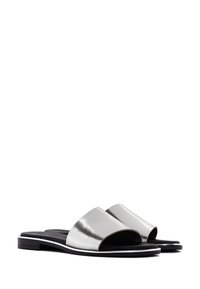 Zilveren faux leren slippers met brede, gebogen banden en platte zwarte zolen, met een minimalistisch ontwerp en zonder versieringen.