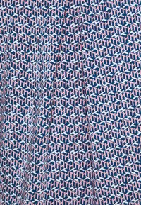 Tissu bleu avec un motif géométrique en rose et blanc, présentant des motifs répétés 'HTH', texture lisse.