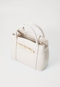 Beige läderhandväska med två handtag ovanpå, med en guld "VALENTINO"-logotyp på framsidan, och en strukturerad, rektangulär design.