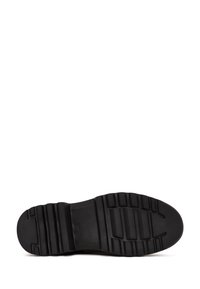 Semelle de chaussures en caoutchouc noir avec un motif de grip texturé ; présente des lignes et des blocs surélevés pour l'adhérence ; design de bout arrondi.