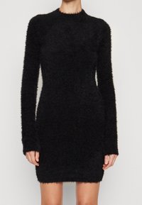 Czarna sukienka z długim rękawem wykonana z miękkiego, puszystego materiału, o dopasowanym kroju, zaokrąglonym dekolcie, miękkiej teksturze oraz prążkowanych mankietach na rękawach i u dołu sukienki.