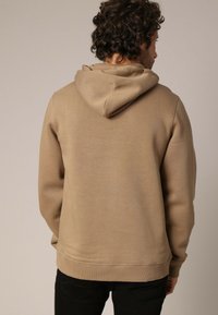 Een hooded sweatshirt in een lichtbruine tint, met een zachte textuur, geribbelde manchetten en een relaxte pasvorm. Geen zichtbare patronen of graphics.