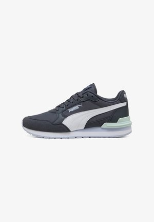 Sötét szürke Puma tornacipők fehér akcentusokkal, sima szövet felsőrésszel, párnázott talppal és texturált részletekkel az oldalakon.