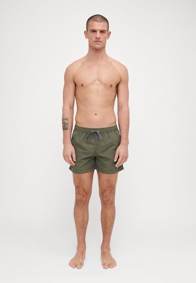 Shorts de bain verts avec une taille élastique et un cordon de serrage. Fabriqués en matériau léger, avec une texture lisse et une longueur au-dessus du genou.