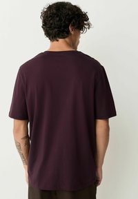 Vinröd kortärmad T-shirt i avslappnad passform, tillverkad av mjuk bomull med en slät yta. Enkel rund halsringning och inga synliga logotyper eller mönster.