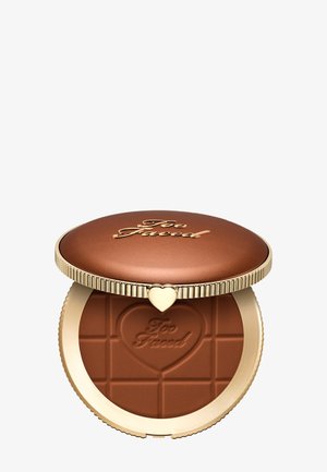 Kompaktes Bronzer-Puder mit goldfarbenem Deckel und herzförmigem Verschluss, geprägt mit „Too Faced“ auf Deckel und Puderoberfläche.