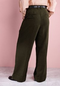 Wide-leg trousers in dark green fabric, featuring a smooth texture, flat front pockets, and a black belt at the waist.