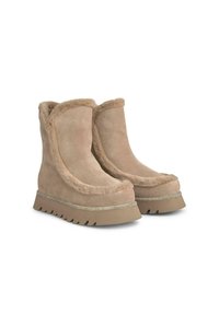 Bottines en suède beige avec doublure en fausse fourrure, design arrondi, semelle épaisse à rayures et bande métallique décorative à la base.