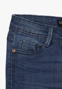 Tmav�ě modré džíny z denimu s klasickým pětikapsovým designem, detaily z měděných cvočků a texturovanou látkou s mírným pružením.